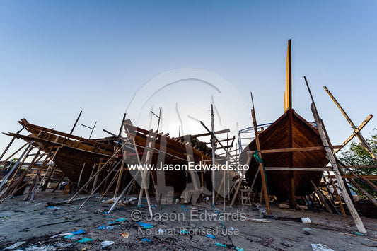 Scaffolding and raw timber planks on the bows of dhows during construction. Sur, Ash Sharqiyah Region, Gulf of Oman, Sultanate of Oman.