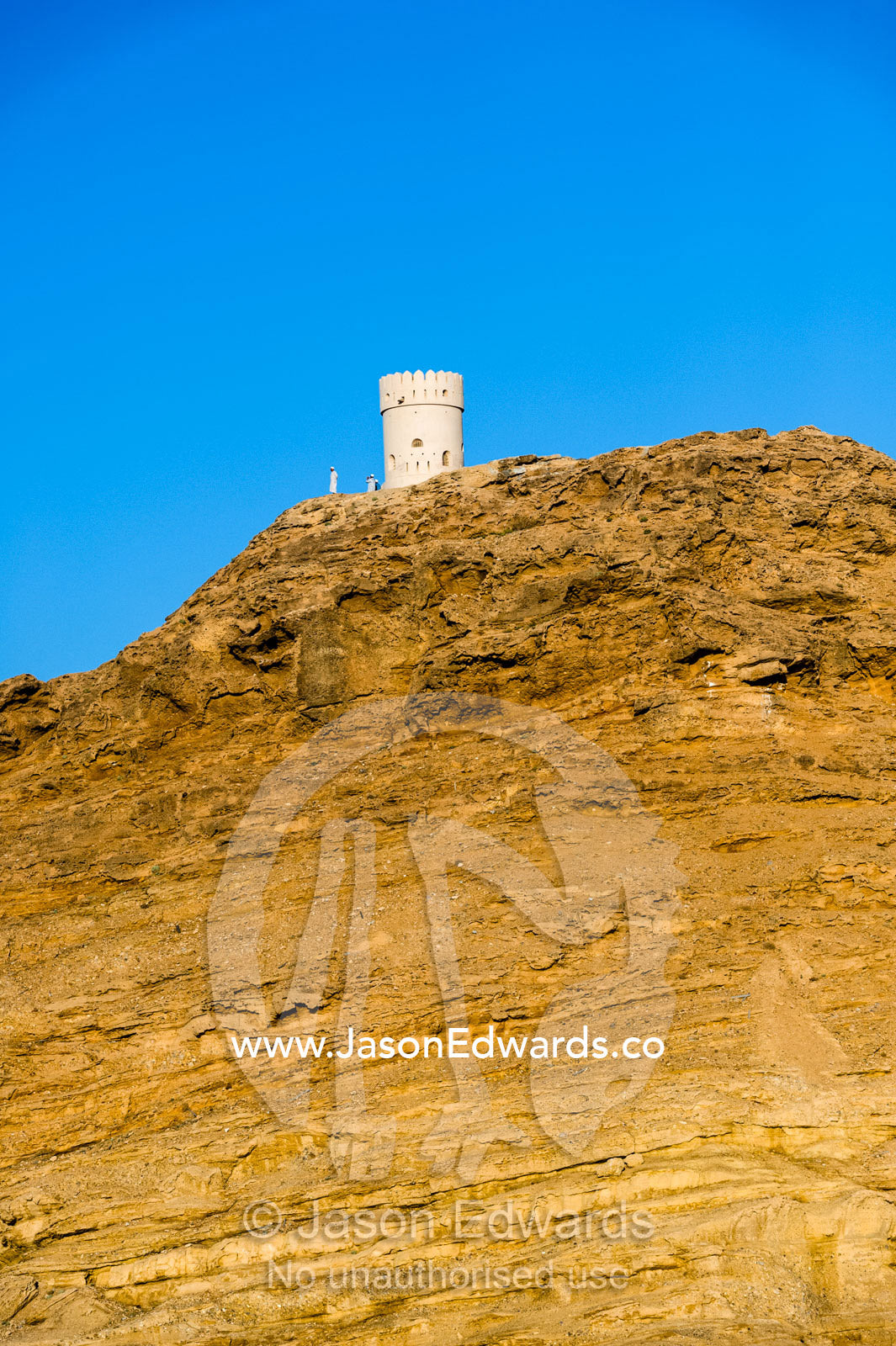 A cylindrical fort watch tower rests on top of a desert cliff overlooking the Gulf of Oman. Sur, Ash Sharqiyah Region, Gulf of Oman, Sultanate of Oman.