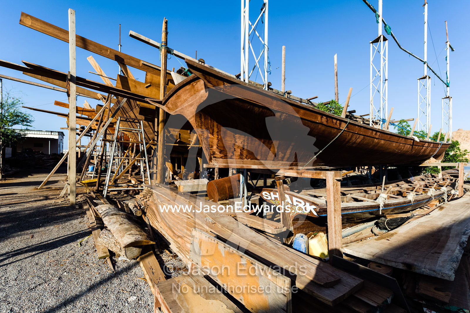 Timber scaffolding supports the hull during handmade construction of an ancient timber dhow. Sur, Ash Sharqiyah Region, Gulf of Oman, Sultanate of Oman.