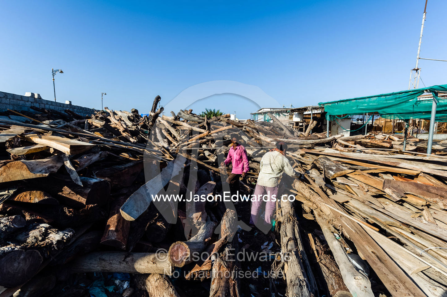 Laborers choose timber the handmade construction of an ancient timber dhow in a ship building yard. Sur, Ash Sharqiyah Region, Gulf of Oman, Sultanate of Oman.
