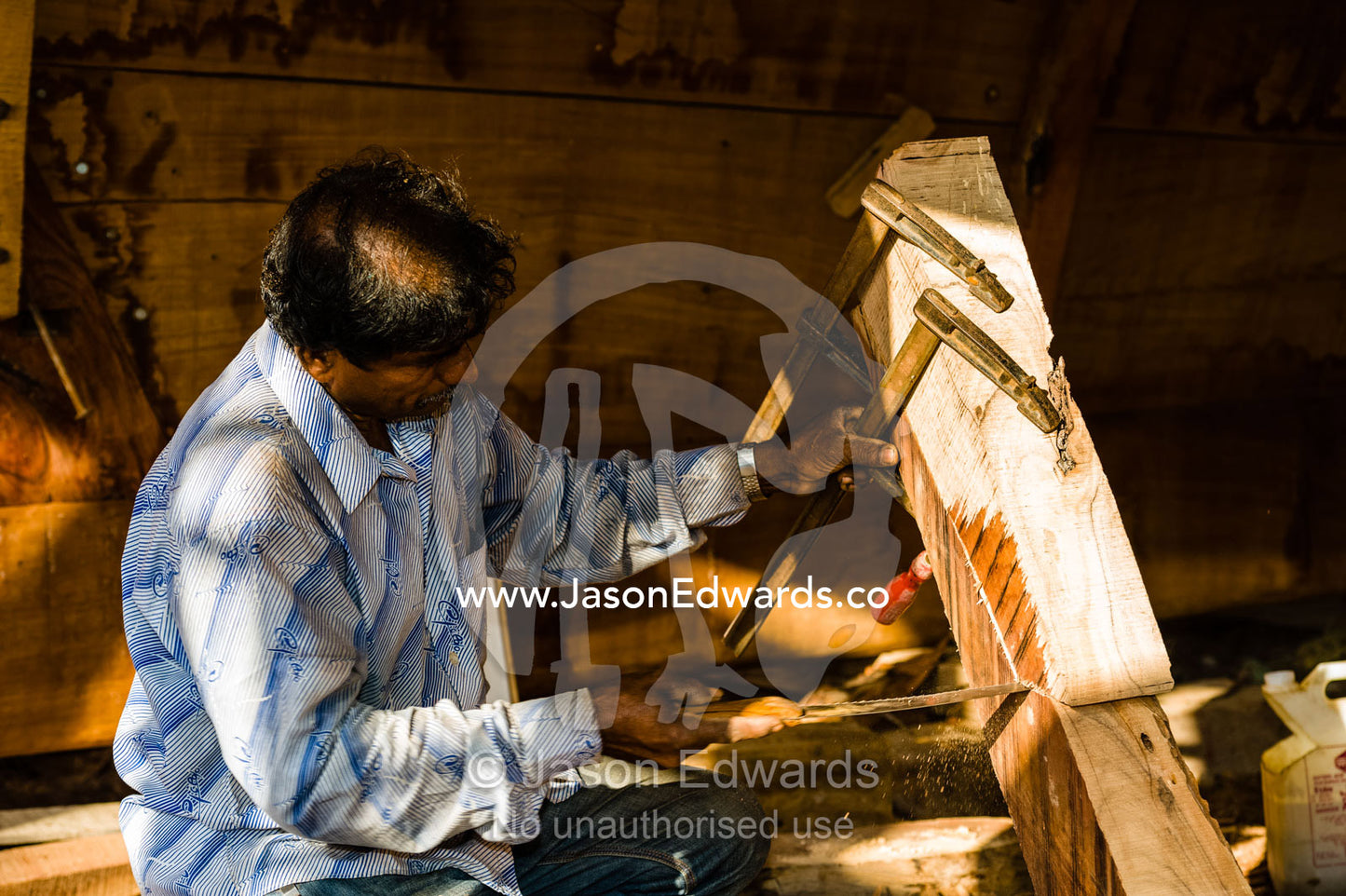 Laborers saw and shape timber hull ribs during handmade construction of an ancient timber dhow. Sur, Ash Sharqiyah Region, Gulf of Oman, Sultanate of Oman.