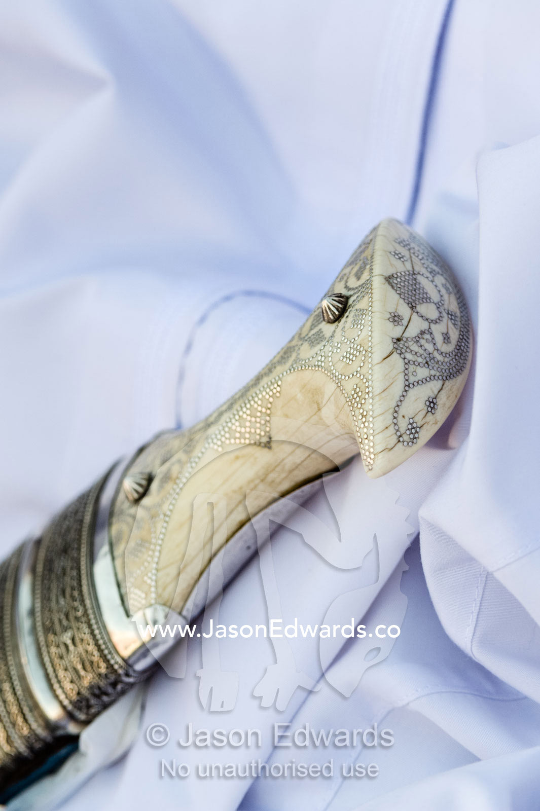 The ornate filigree and embossing on a silver and ivory khanjar worn by a man at a camel race. Bidiya, Sharqiya Region, Sultanate of Oman.