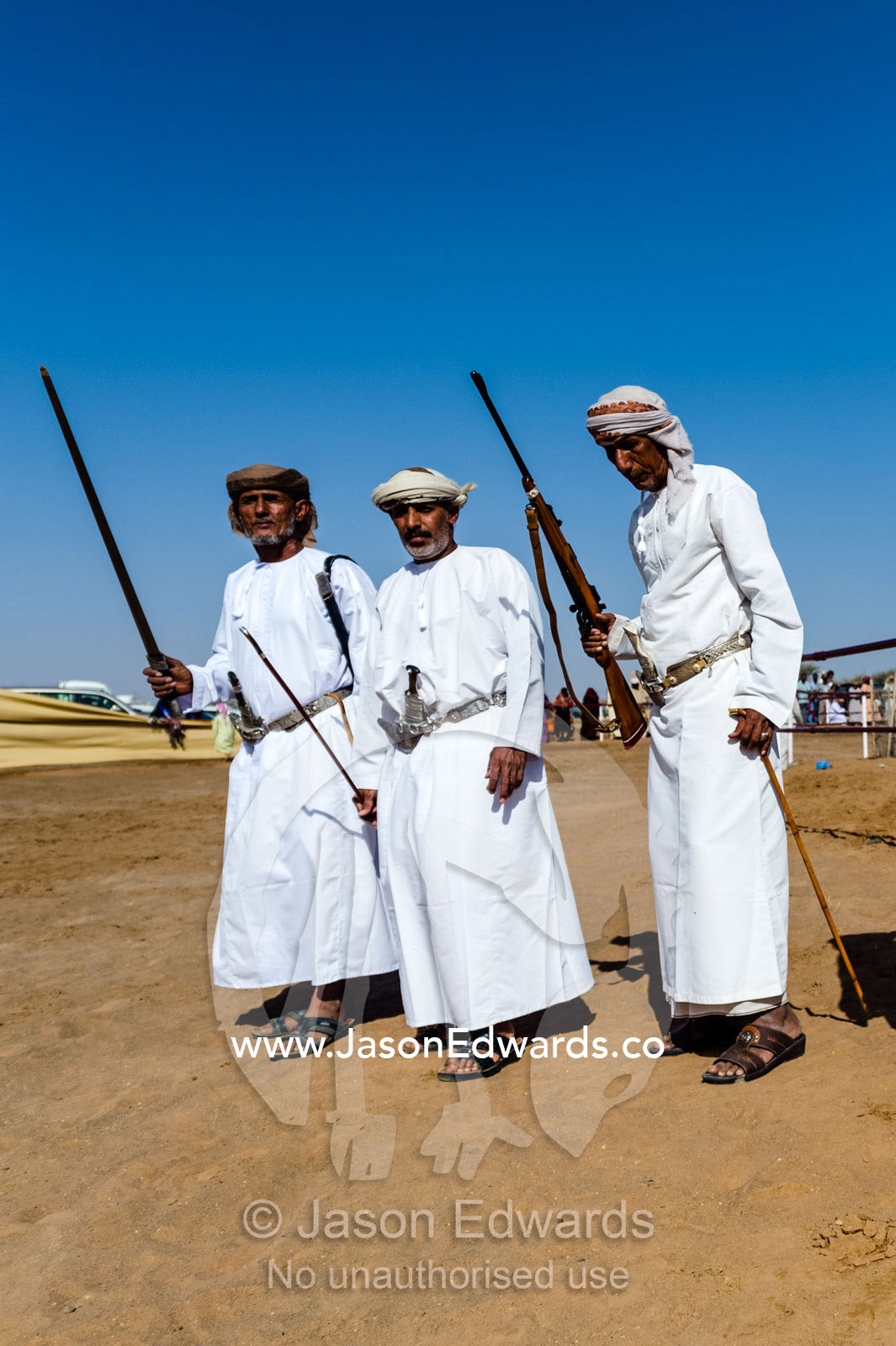 Members of a traditional Omani band carry swords and rifles during a performance at a camel race. Bidiya, Sharqiya Region, Sultanate of Oman.