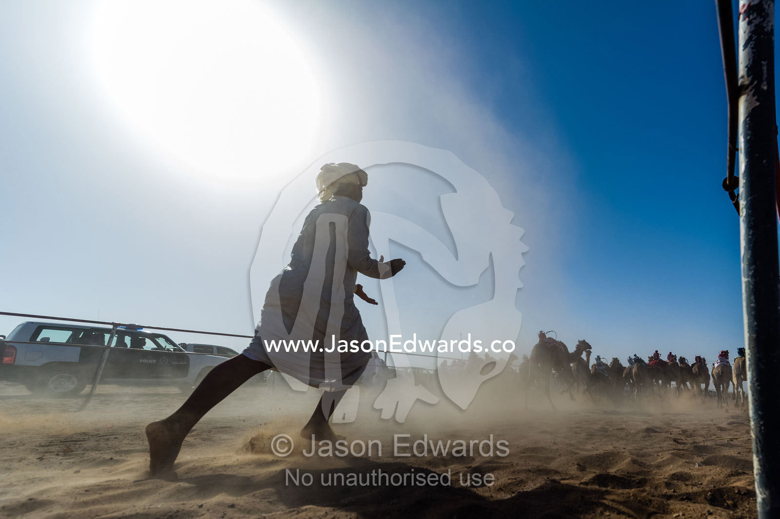 A camel handler runs after the camels at the start of a race clapping his hands to encourage them. Bidiya, Sharqiya Region, Sultanate of Oman.
