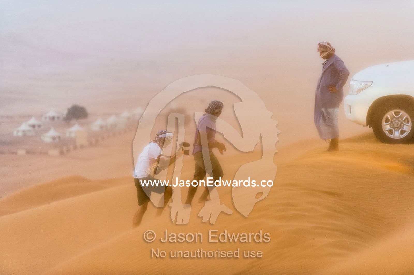 A television cameramen climbs a dune while filming during a sand storm. Wahiba Sands, Ramlat al-Wahiba, Sharqiya Sands, Sultanate of Oman.