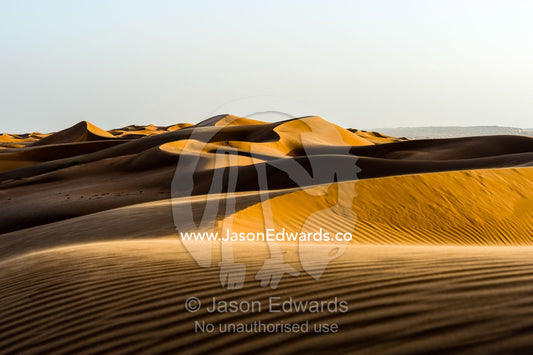 Windblown ripples and sand patterns on the surface of a red sand dune at sunset. Wahiba Sands, Ramlat al-Wahiba, Sharqiya Sands, Sultanate of Oman.
