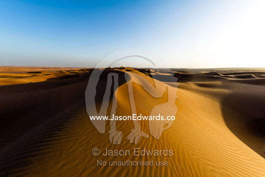 Windblown ripples and sand patterns on the surface of a red sand dune at sunset. Wahiba Sands, Ramlat al-Wahiba, Sharqiya Sands, Sultanate of Oman.
