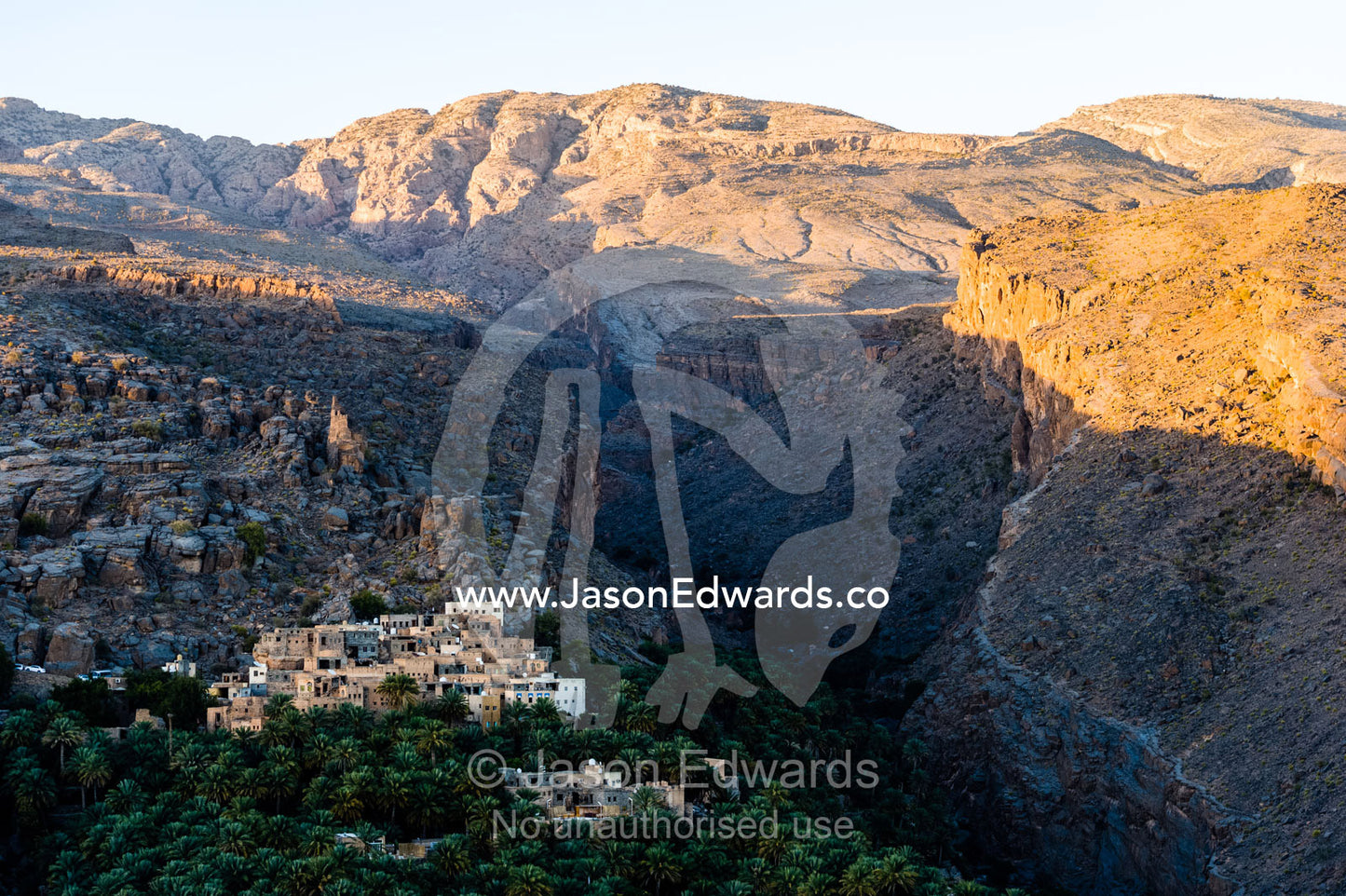 An ancient mud brick village on a desert gorge mountainside surrounded by palm trees. Misfat Al Abryeen, Al Hajar Mountains, Al Hamra, Ad Dakhiliyah Region, Sultanate of Oman.