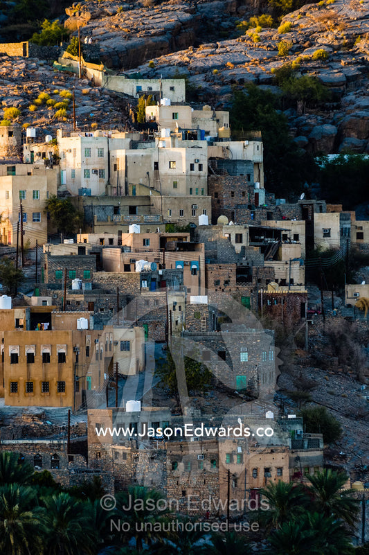 An ancient mud brick village on a desert gorge mountainside surrounded by palm trees. Misfat Al Abryeen, Al Hajar Mountains, Al Hamra, Ad Dakhiliyah Region, Sultanate of Oman.