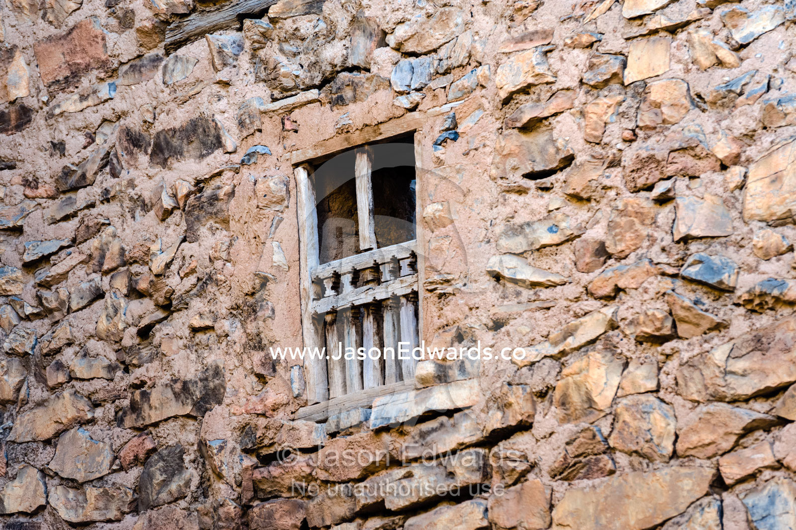 A timber window frame and wooden bars in an ancient mud brick village wall. Misfat Al Abryeen, Al Hajar Mountains, Al Hamra, Ad Dakhiliyah Region, Sultanate of Oman.