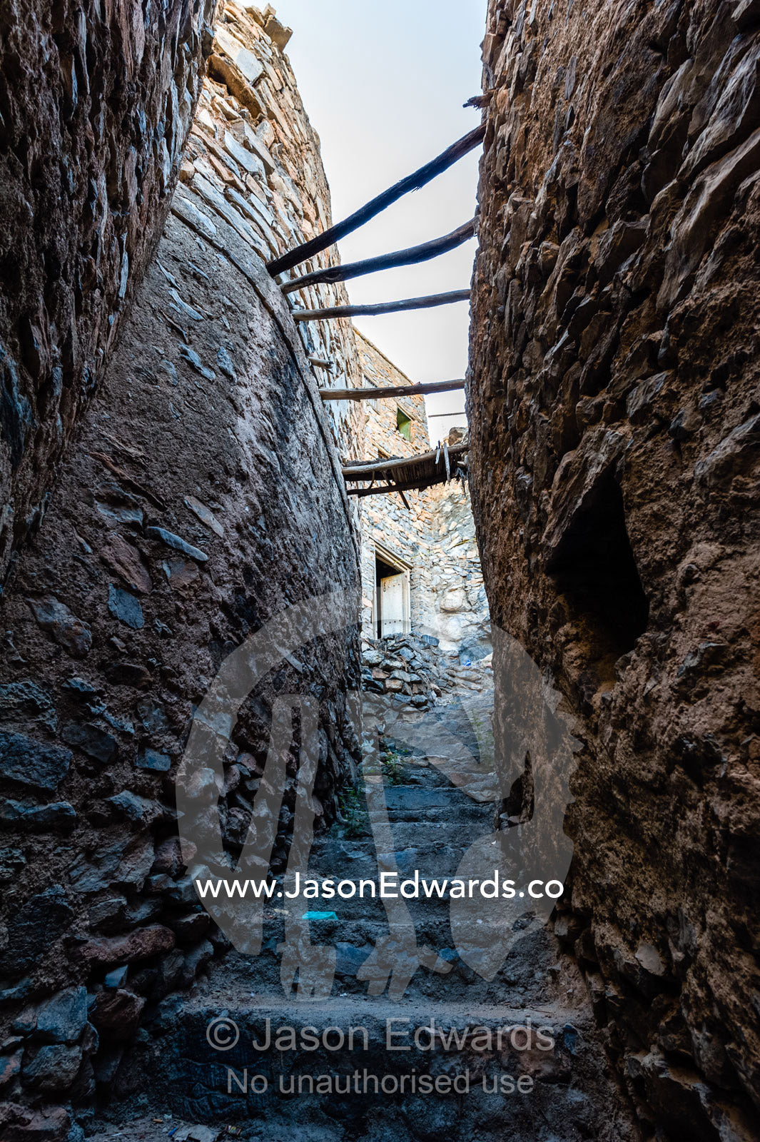 Stone steps through a narrow mud brick alleyway in an ancient mud brick village in the desert. Misfat Al Abryeen, Al Hajar Mountains, Al Hamra, Ad Dakhiliyah Region, Sultanate of Oman.