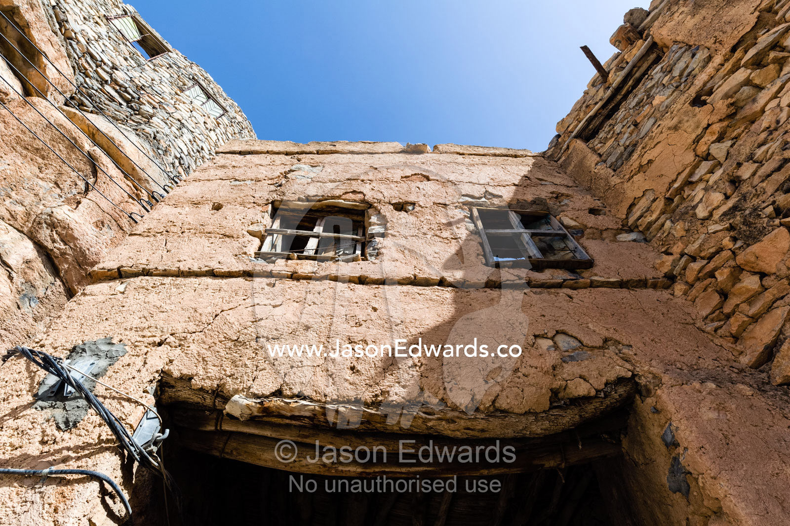Timber framed windows in a room bridging a mud brick alleyway in an ancient village in the desert. Misfat Al Abryeen, Al Hajar Mountains, Al Hamra, Ad Dakhiliyah Region, Sultanate of Oman.