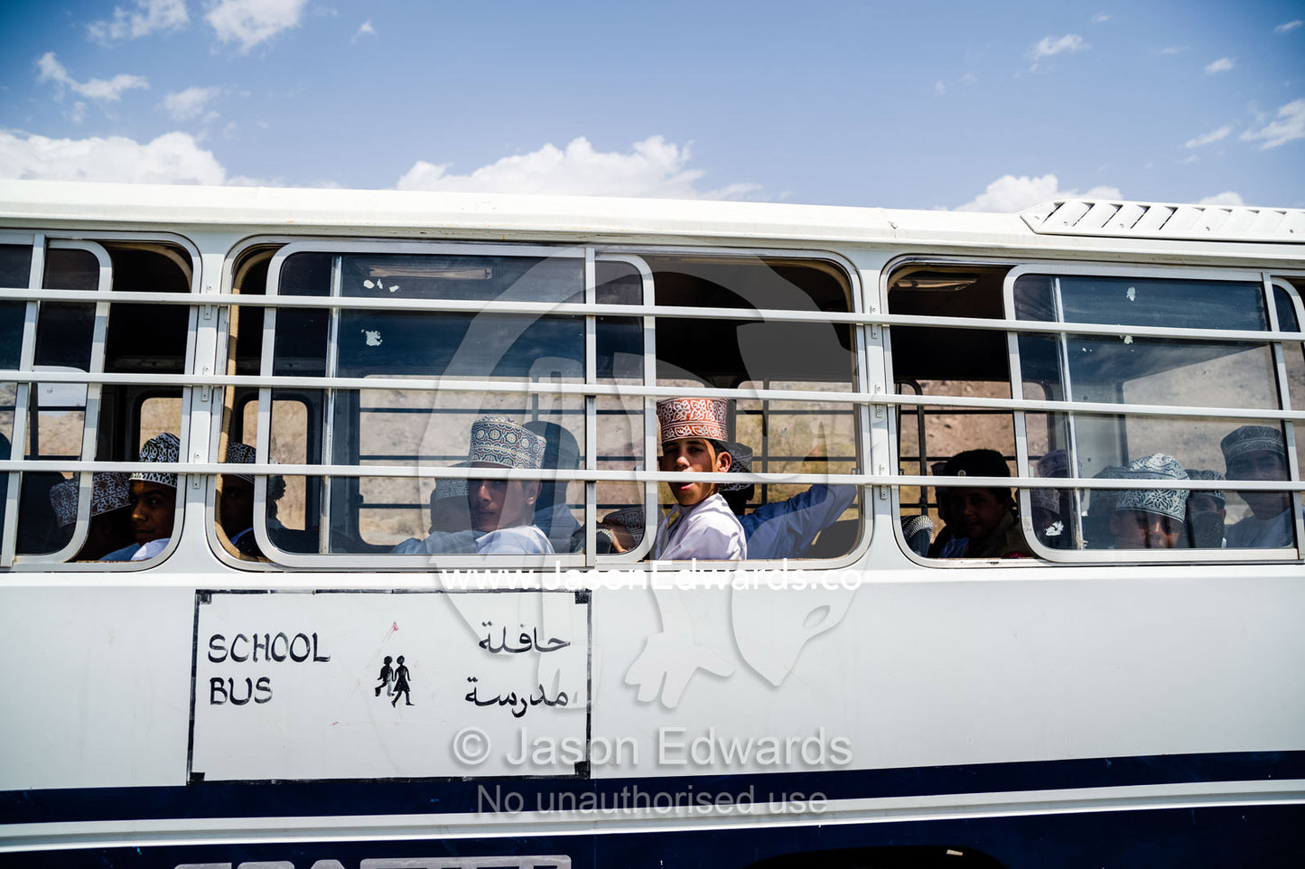 Muslim school boys travel on a bus through the desert. Jebel Shams, Al Hajar Mountains, Sultanate of Oman.