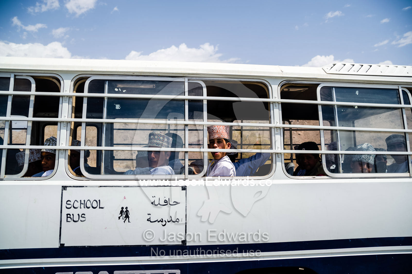 Muslim school boys travel on a bus through the desert. Jebel Shams, Al Hajar Mountains, Sultanate of Oman.