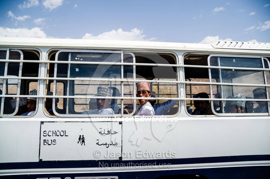 Muslim school boys travel on a bus through the desert. Jebel Shams, Al Hajar Mountains, Sultanate of Oman.