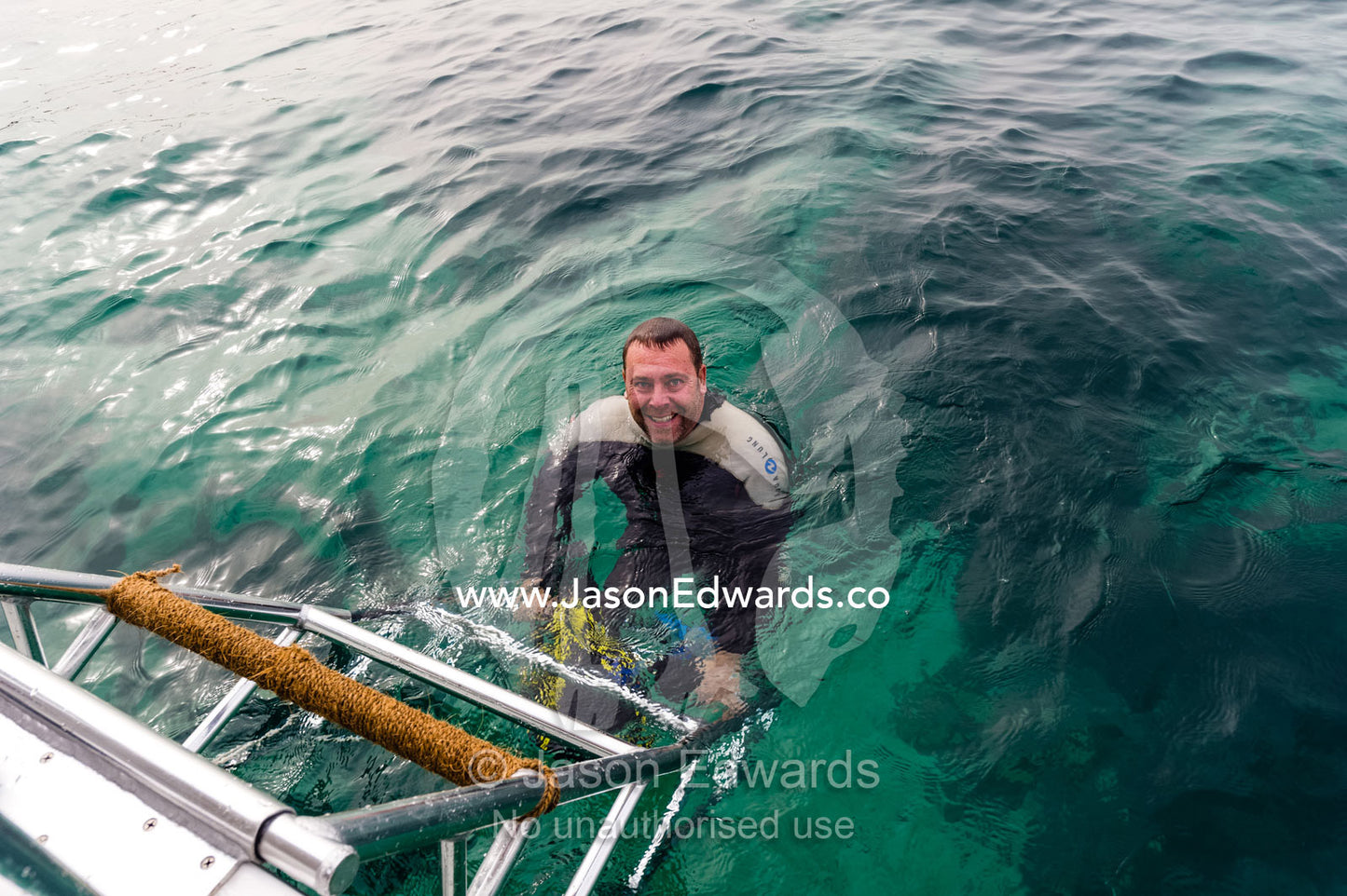 A scuba diver prepares to climb a boat ladder out of the ocean. Daymaniyat Islands Nature Reserve, Wilayat AlSeeb, Barka, Sultanate of Oman.