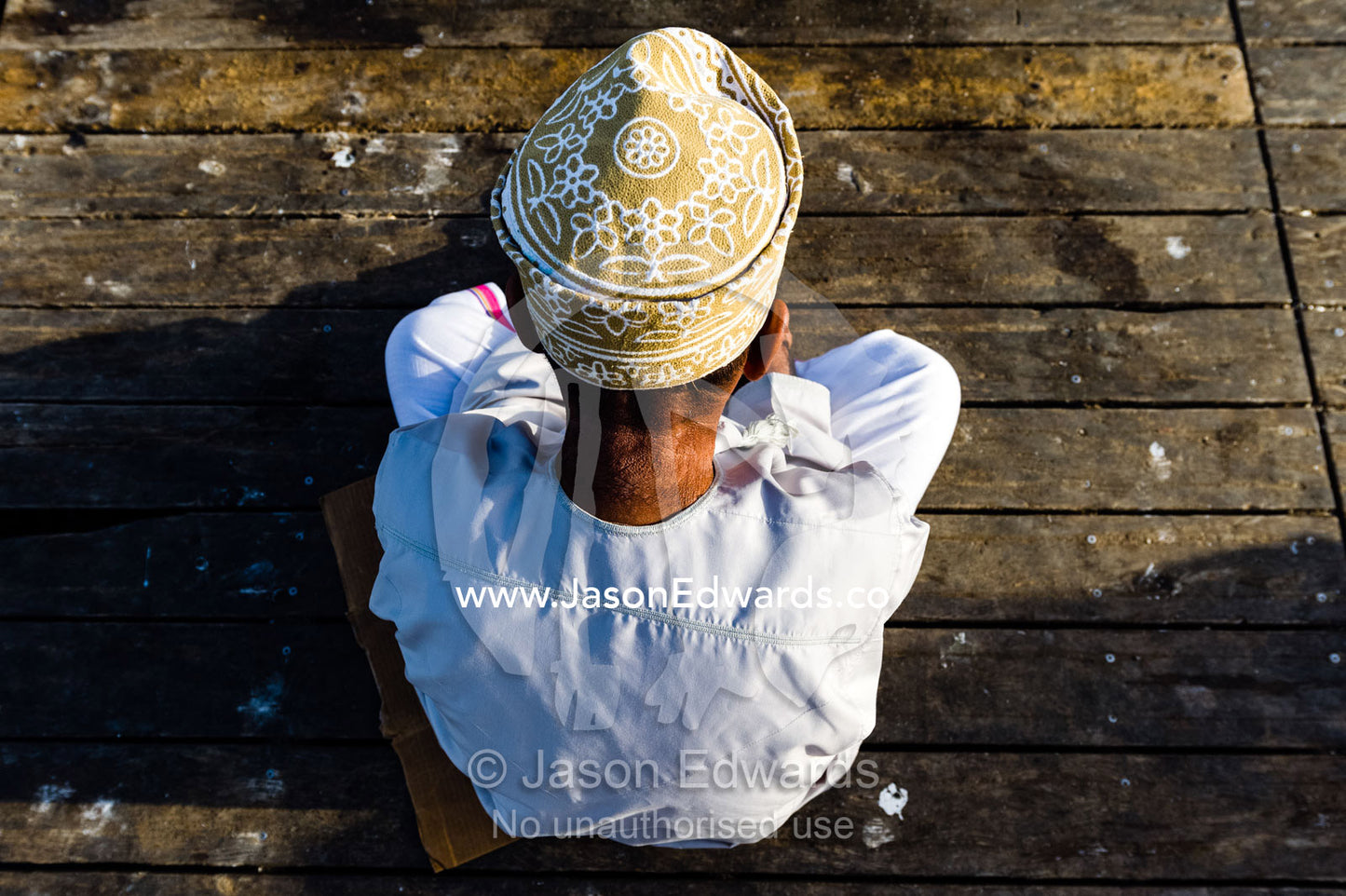 A Muslim man wearing a traditional kuma sitting on a fish market jetty. Mutrah Fish Market, Muscat, Gulf of Oman, Sultanate of Oman.