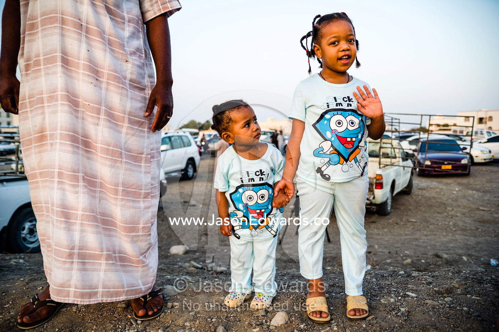 Young sisters watch a traditional bull fight with their father. Al Sharadi, Seeb, Muscat, Sultanate of Oman.