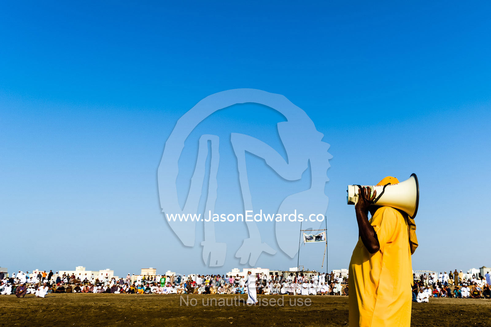 An comedian with a megaphone entertains the crowd at a traditional bullfight. Al Sharadi, Seeb, Muscat, Sultanate of Oman.