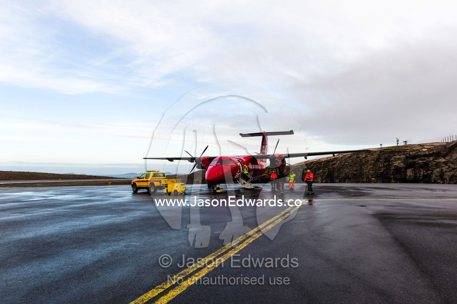 A passenger aircraft waiting for boarding on a wet tarmac. Maniitsoq, Sukkertoppen, Qeqqata Municipality, Greenland.