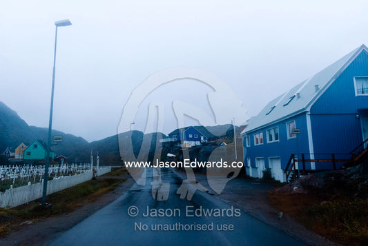 Evening descends over a wet road running through a fishing village. Maniitsoq, Sukkertoppen, Qeqqata Municipality, Greenland.