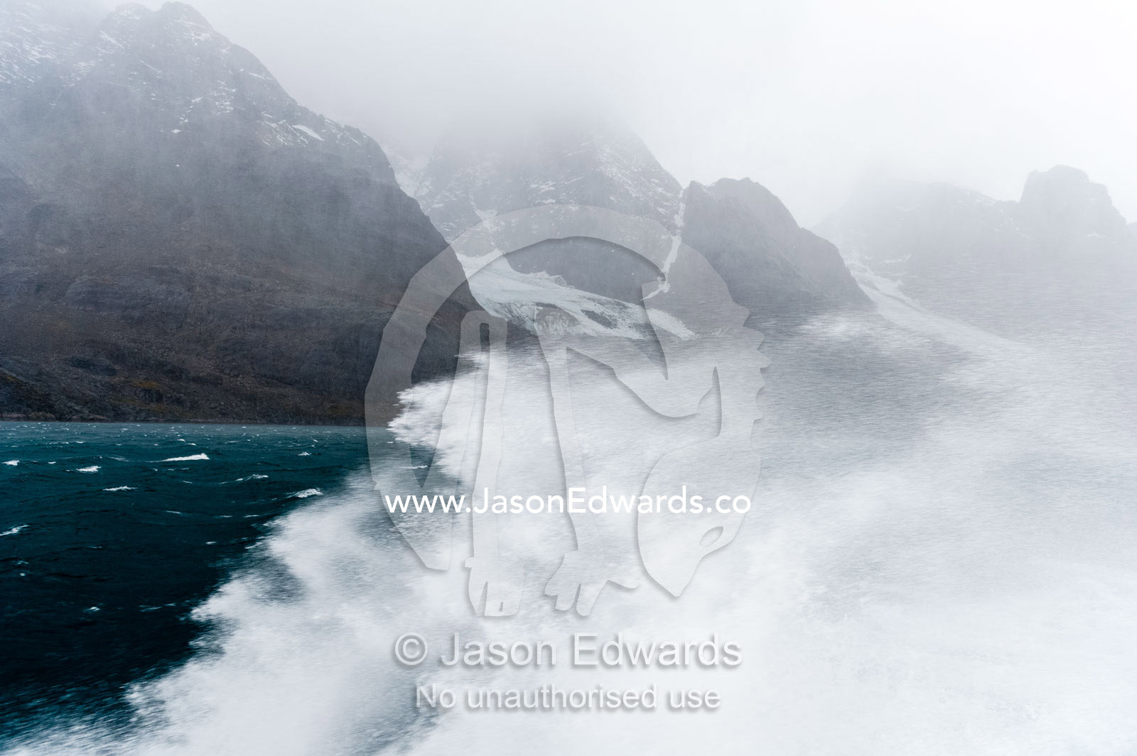 A boats passage through rough seas sends waves and spray into the air beneath jagged mountains. Fjord of Eternity, Maniitsoq, Sukkertoppen, Qeqqata Municipality, Greenland.