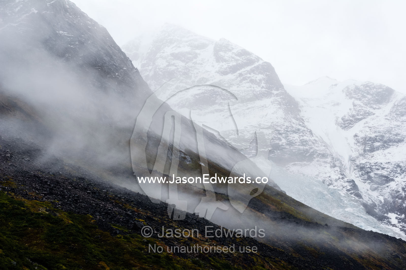 Cloud and mist shroud jagged and rugged mountain peaks during a rain storm in a fiord. Fjord of Eternity, Maniitsoq, Sukkertoppen, Qeqqata Municipality, Greenland.