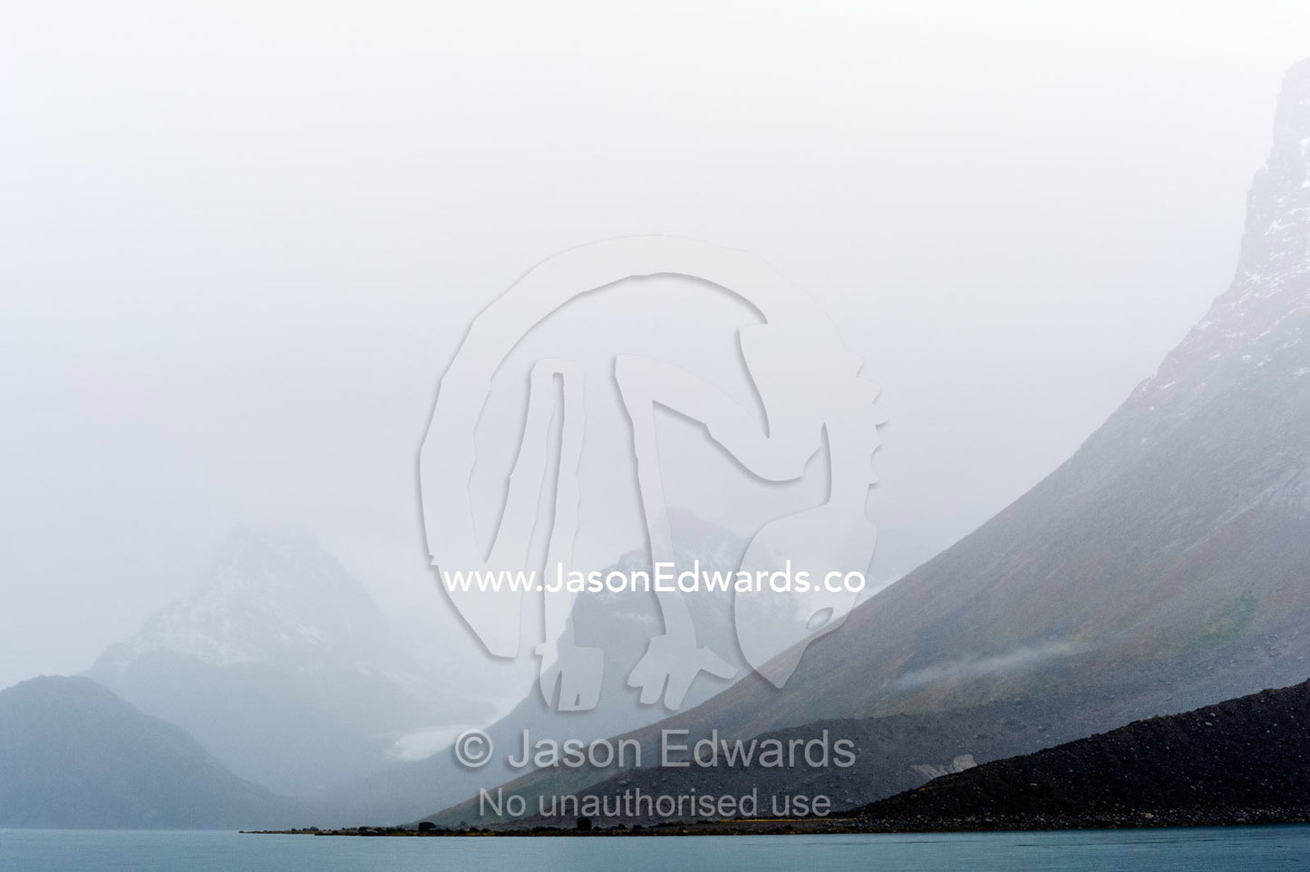 Cloud and mist shroud jagged and rugged mountain peaks during a rain storm in a fiord. Fjord of Eternity, Maniitsoq, Sukkertoppen, Qeqqata Municipality, Greenland.