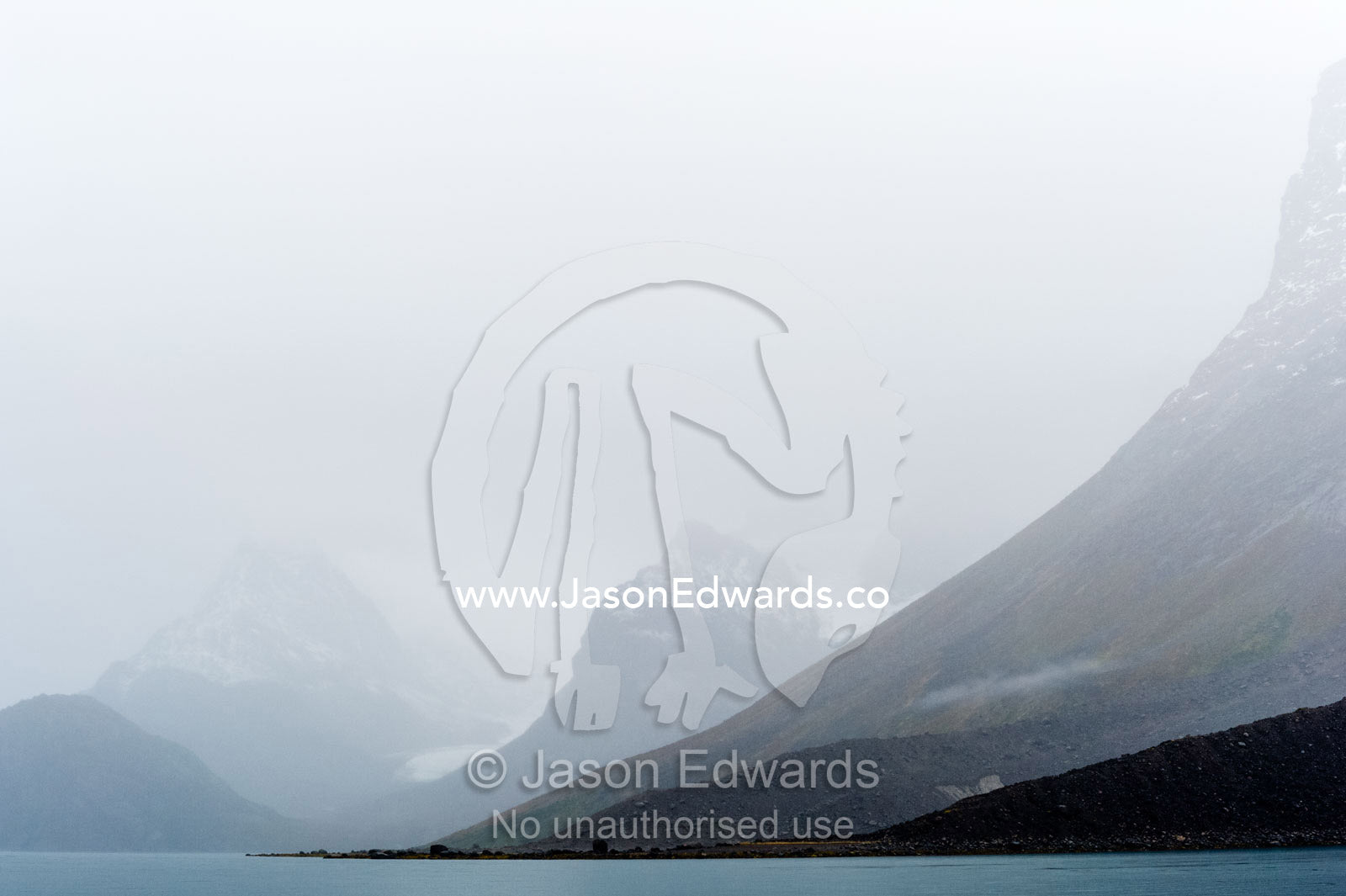 Cloud and mist shroud jagged and rugged mountain peaks during a rain storm in a fiord. Fjord of Eternity, Maniitsoq, Sukkertoppen, Qeqqata Municipality, Greenland.