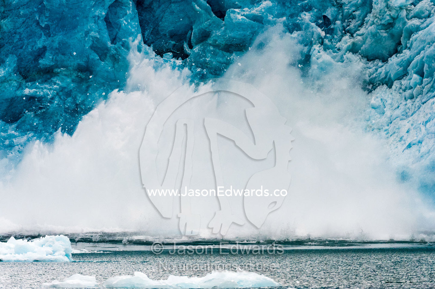 Spray and waves fly into the air after ice carves from a glacier into a fjord. Fjord of Eternity, Maniitsoq, Sukkertoppen, Qeqqata Municipality, Greenland.