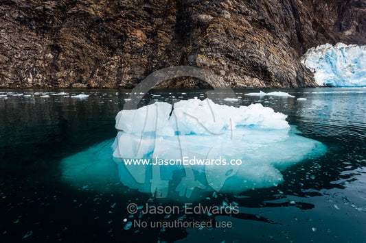 An iceberg floating in the dark waters of an Arctic fjord. Fjord of Eternity, Maniitsoq, Sukkertoppen, Qeqqata Municipality, Greenland.