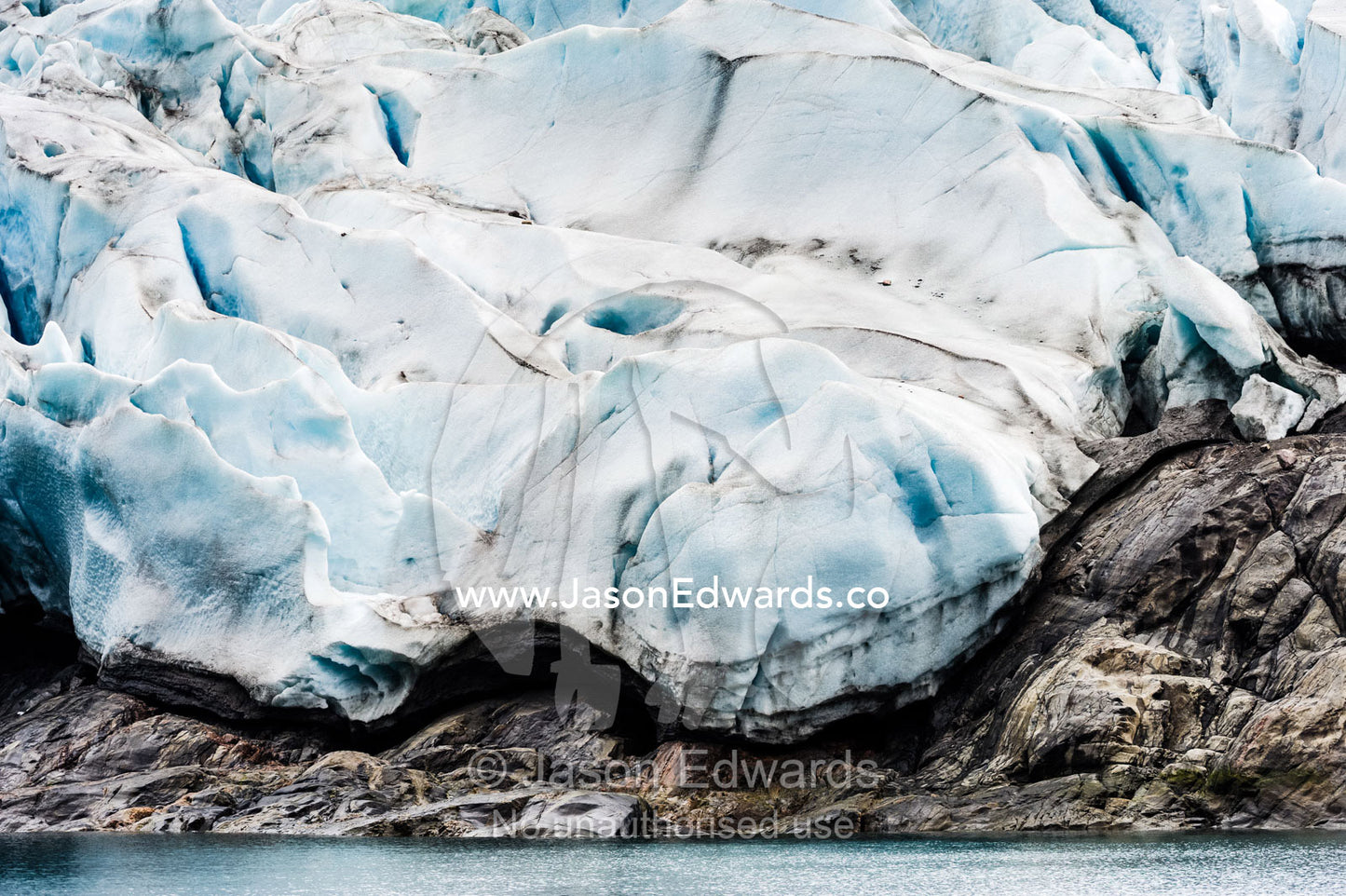 A jagged glacier tongue recedes up a rugged and inhospitable mountain in a fiord. Fjord of Eternity, Maniitsoq, Sukkertoppen, Qeqqata Municipality, Greenland.