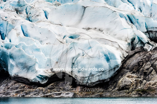 A jagged glacier tongue recedes up a rugged and inhospitable mountain in a fiord. Fjord of Eternity, Maniitsoq, Sukkertoppen, Qeqqata Municipality, Greenland.