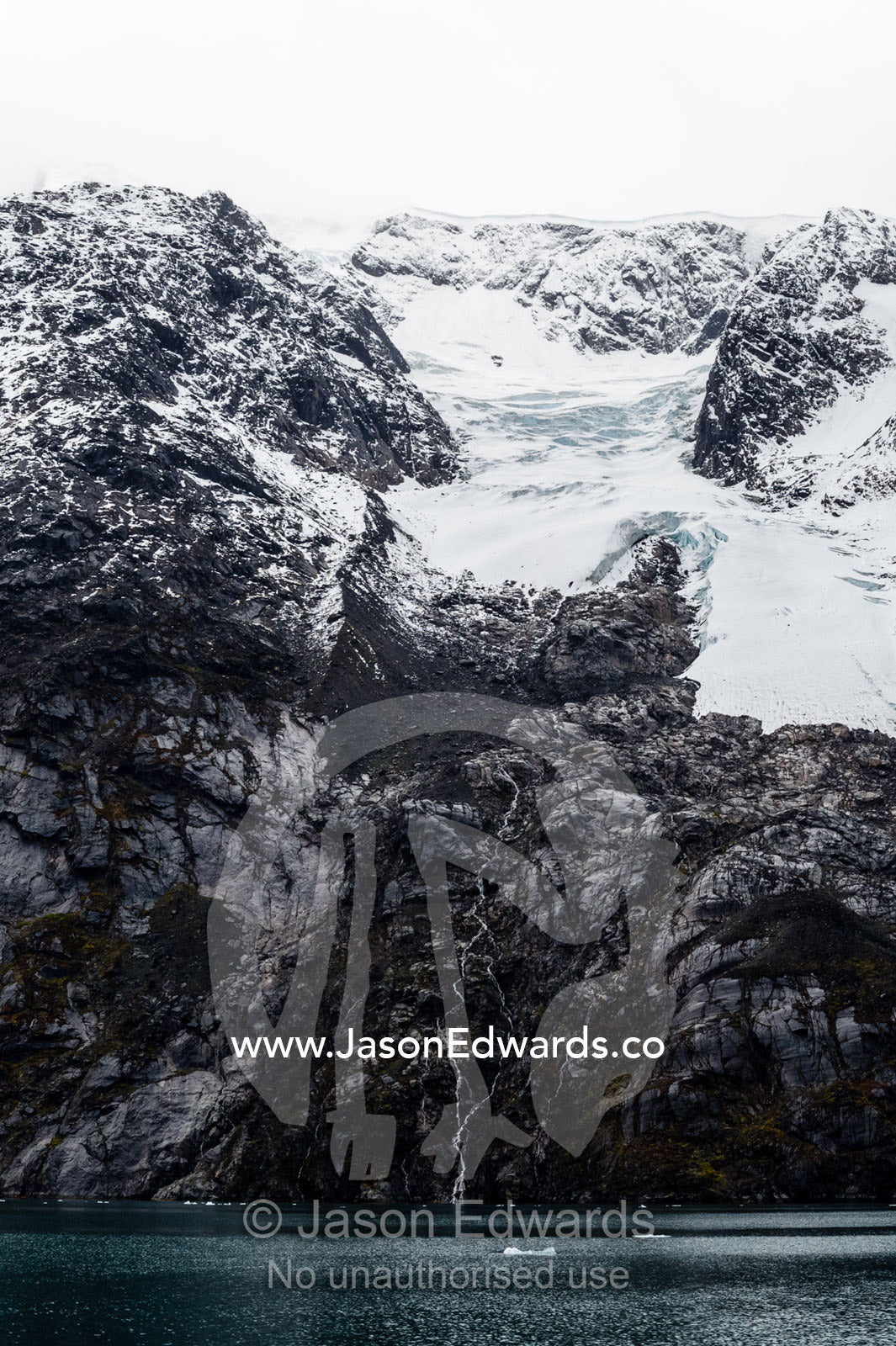 A glacier receding up a mountainside exposes barren rock. Fjord of Eternity, Maniitsoq, Sukkertoppen, Qeqqata Municipality, Greenland.