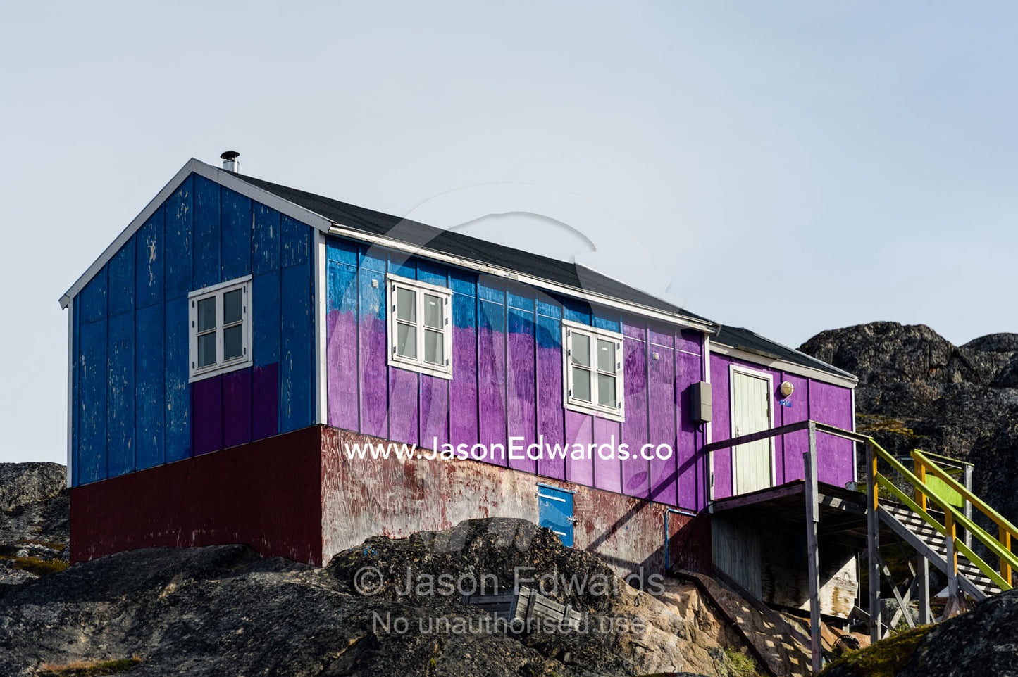 A partially painted house in blue and purple on a rugged island. Kangaamiut, Gammel Sukkertoppen, Qeqqata Municipality, Greenland.