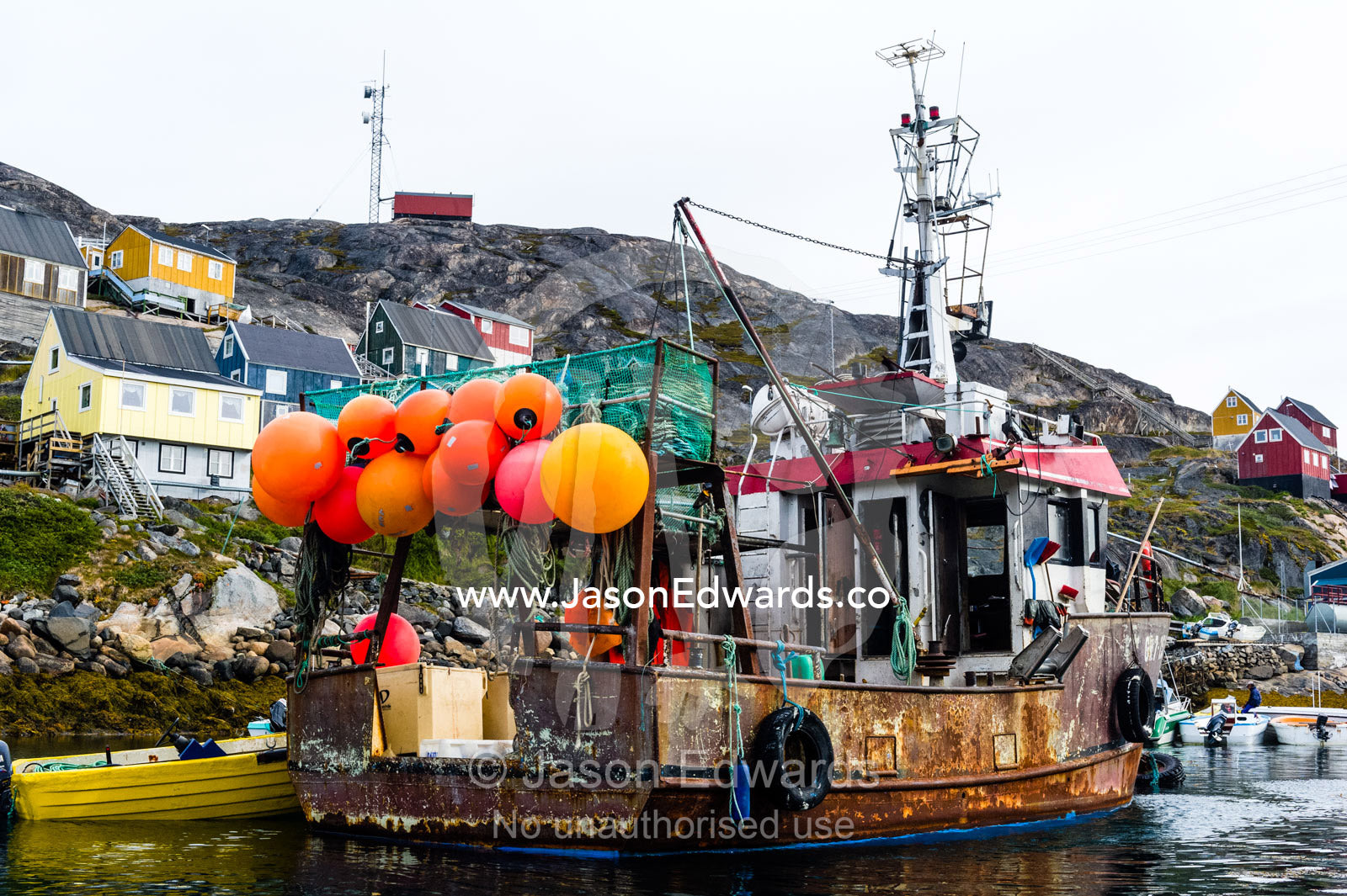 A rusting fishing boat with net buoys moored in a sheltered harbor. Kangaamiut, Gammel Sukkertoppen, Qeqqata Municipality, Greenland.