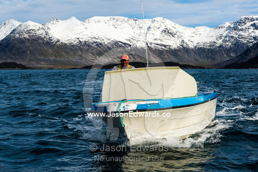 A seal hunter searches for prey in a small boat on the ocean. Davis Strait, Kangaamiut, Gammel Sukkertoppen, Qeqqata Municipality, Greenland.