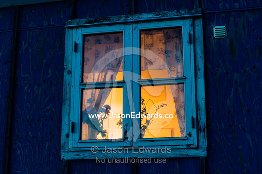 Silhouetted plants in the window of a village cottage at night. Kangaamiut, Gammel Sukkertoppen, Qeqqata Municipality, Greenland.