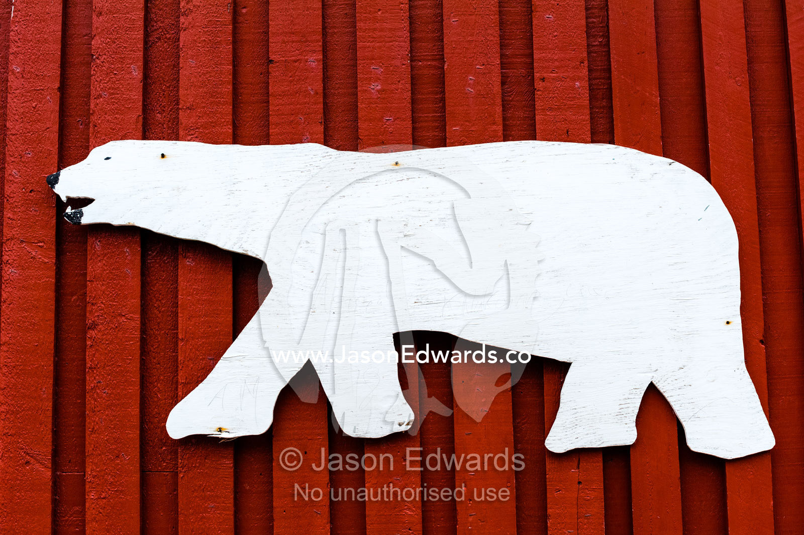A timber polar bear graphic on the wall of red village building. Kangaamiut, Gammel Sukkertoppen, Qeqqata Municipality, Greenland.
