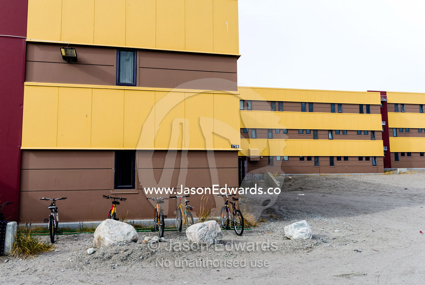A linear apartment complex and barren carpark in an arctic village. Kangerlussuaq, Qeqqata Municipality, Greenland.