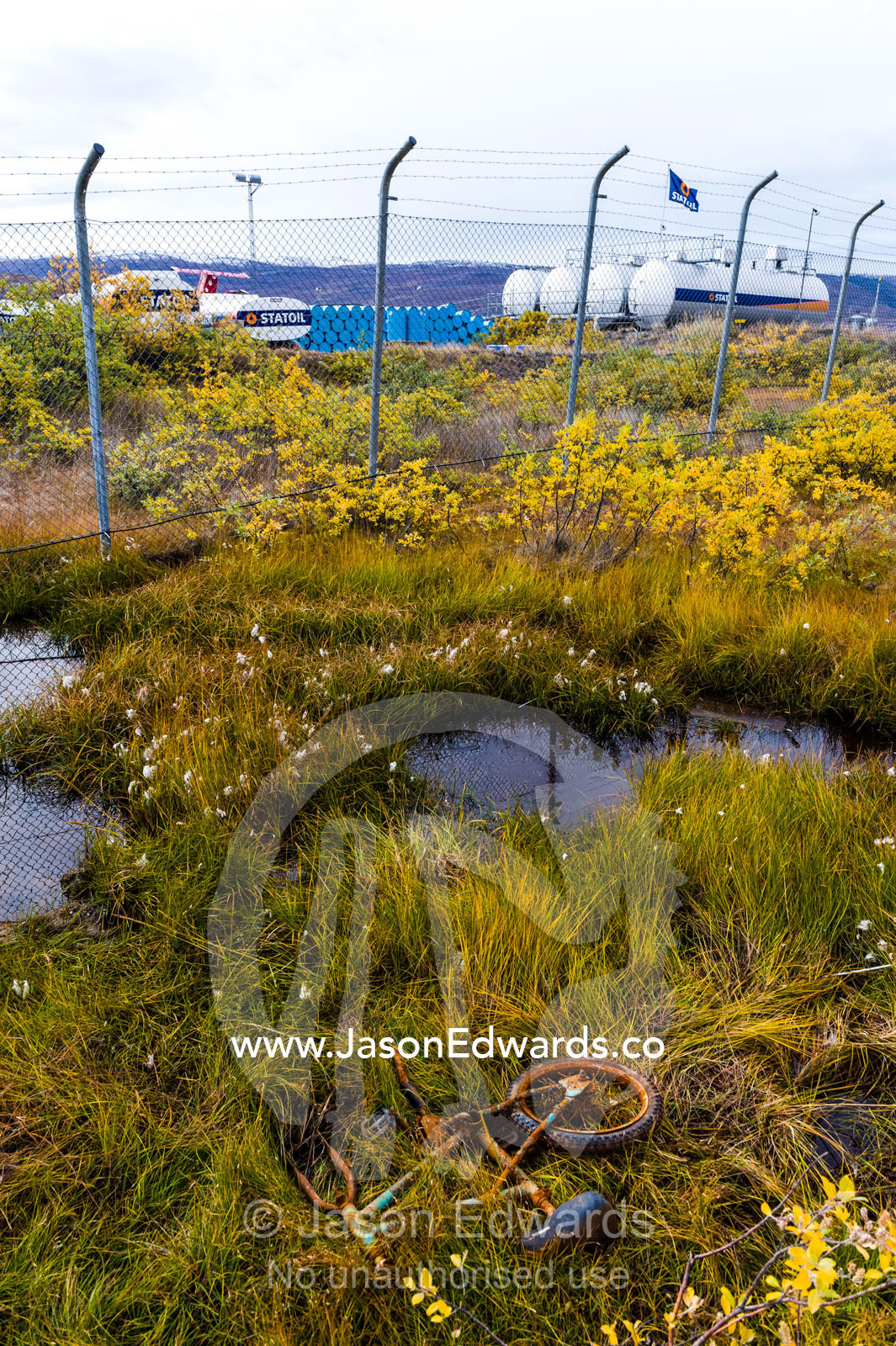A broken children's bike rusting in ditch beside an airfield in an arctic village. Kangerlussuaq, Qeqqata Municipality, Greenland.