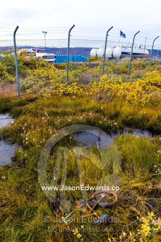 A broken children's bike rusting in ditch beside an airfield in an arctic village. Kangerlussuaq, Qeqqata Municipality, Greenland.