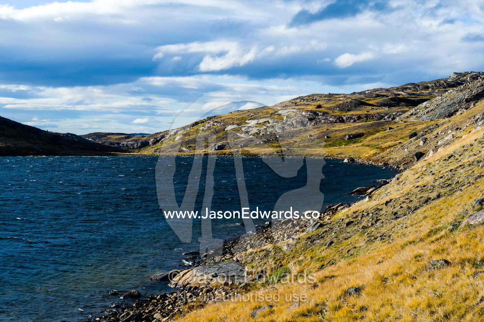 The shoreline and low rolling tundra hills surrounding an alpine lake. Isunngua Highland, Kangerlussuaq, Qeqqata Municipality, Greenland.