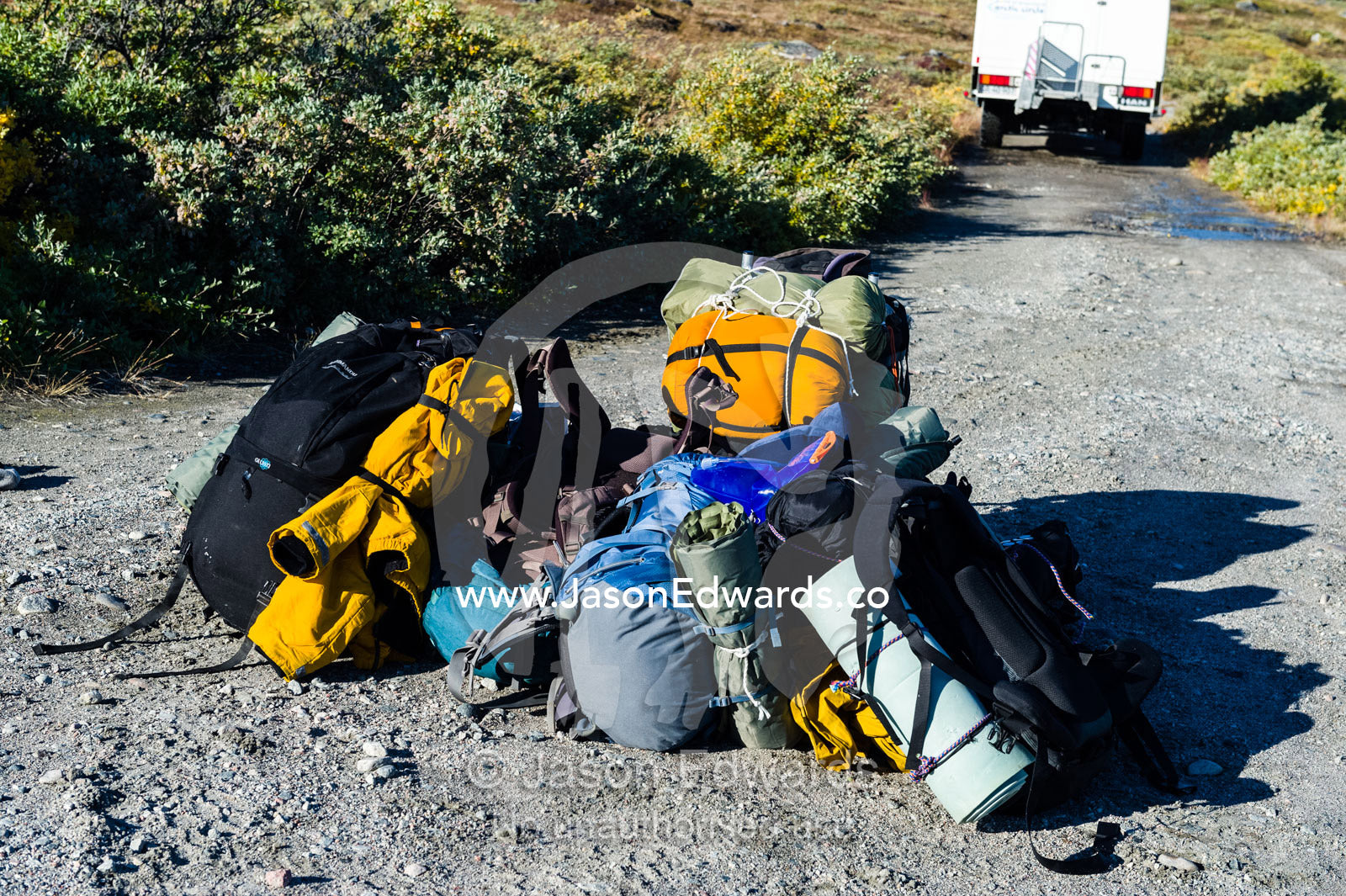 Backpacks dropped by a departing bus wait for hikers to begin their journey. Tasersuatsiaq Lake, Kangerlussuaq, Qeqqata Municipality, Greenland.