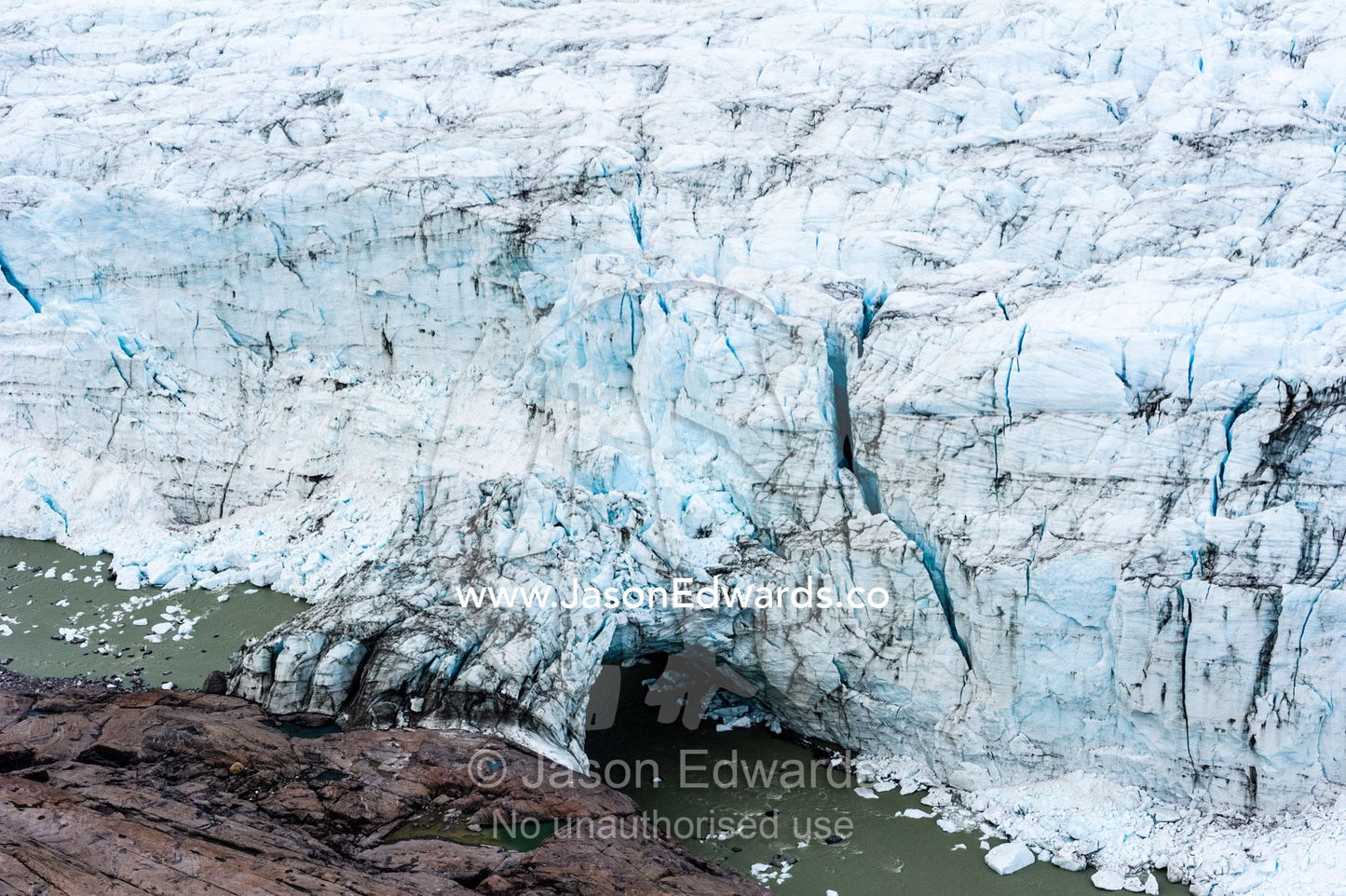 A river running beneath an ice bridge from a glacier fracture zone to the land. Russell Glacier, Greenland Ice Sheet, Qeqqata Municipality, Kangerlussuaq, Greenland.