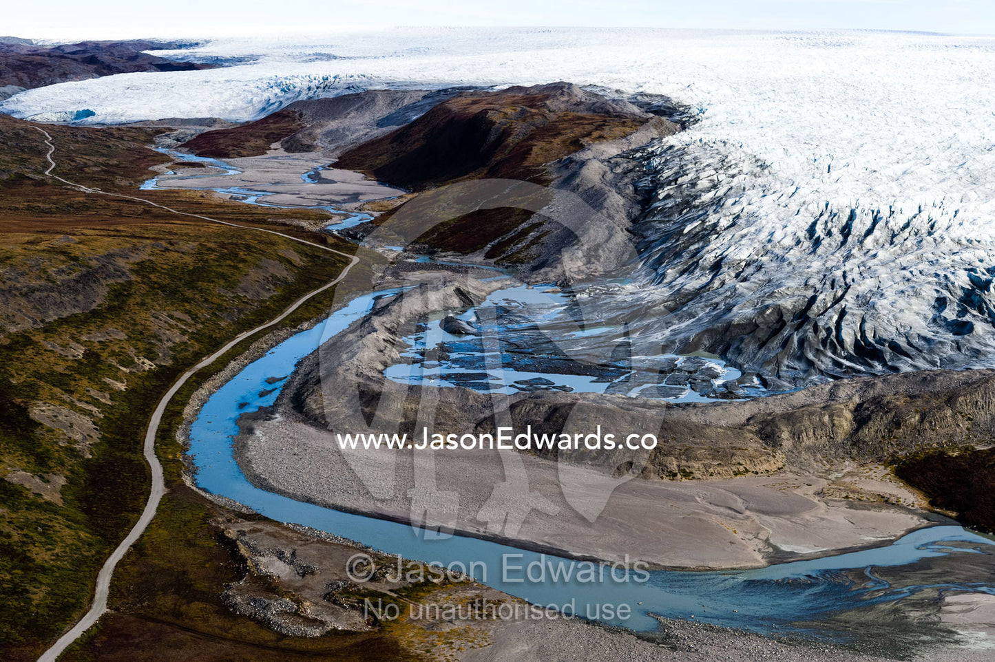 A river skirts a pile of rock, sediment and silt debris deposited by the leading edge of a glacier. Qinnguata Kuussua River, Russell Glacier, Greenland Ice Sheet, Qeqqata Municipality, Kangerlussuaq, Greenland.