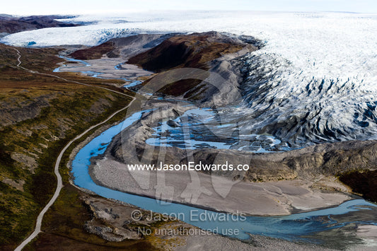 A river skirts a pile of rock, sediment and silt debris deposited by the leading edge of a glacier. Qinnguata Kuussua River, Russell Glacier, Greenland Ice Sheet, Qeqqata Municipality, Kangerlussuaq, Greenland.