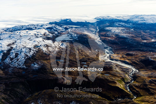 A winding river flows from a glacier and snakes it's way through a highland tundra valley. Tarajornitsut Highlands, Greenland Ice Sheet, Qeqqata Municipality, Kangerlussuaq, Greenland.