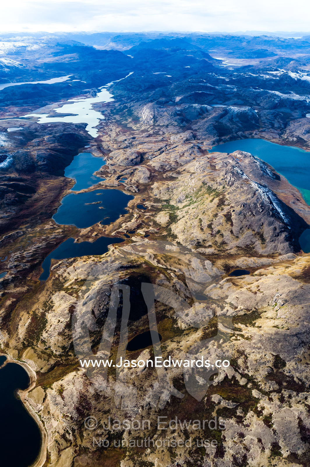 Barren rocky mountaintops surround pristine alpine lakes on a highland tundra. Tarajornitsut Highlands, Qeqqata Municipality, Kangerlussuaq, Greenland.