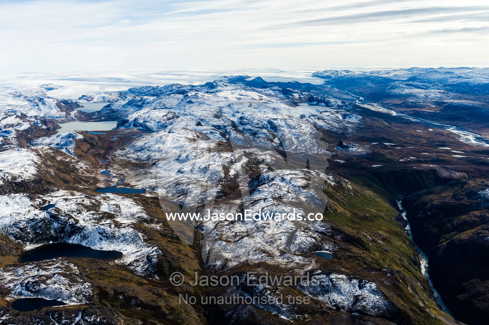 A dusting of snow covers mountain peaks on a highland tundra plateau. Tarajornitsut Highlands, Qeqqata Municipality, Kangerlussuaq, Greenland.